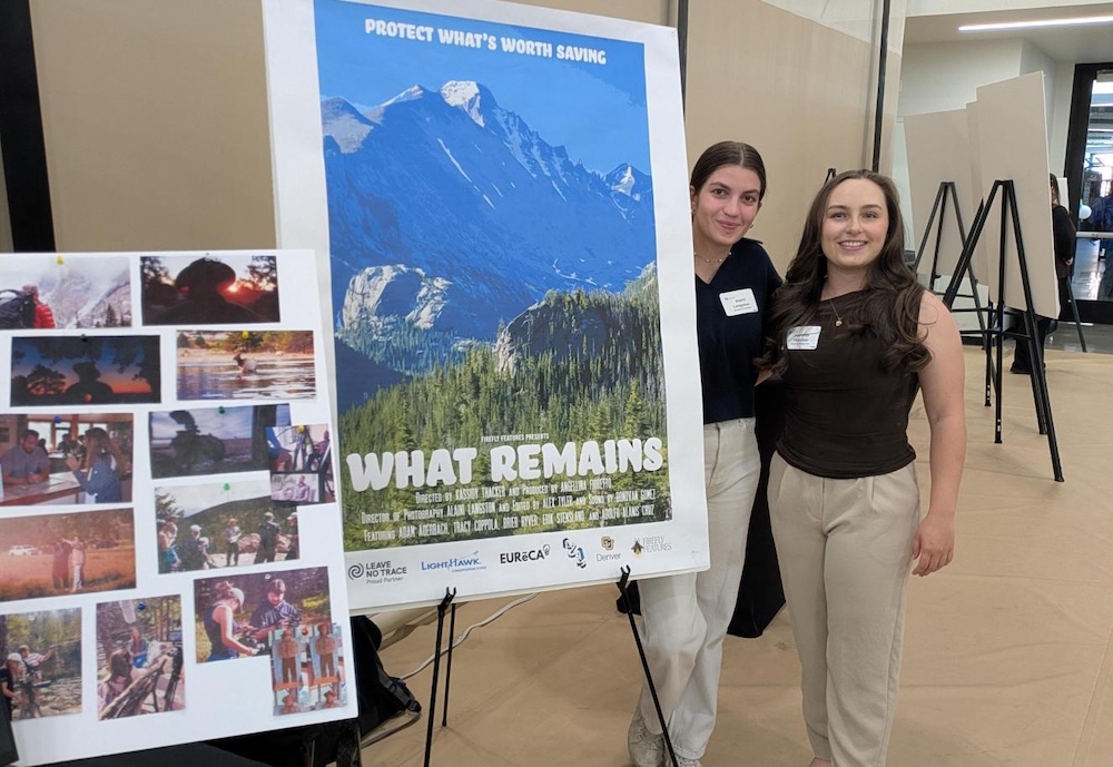 two people standing next to a film poster