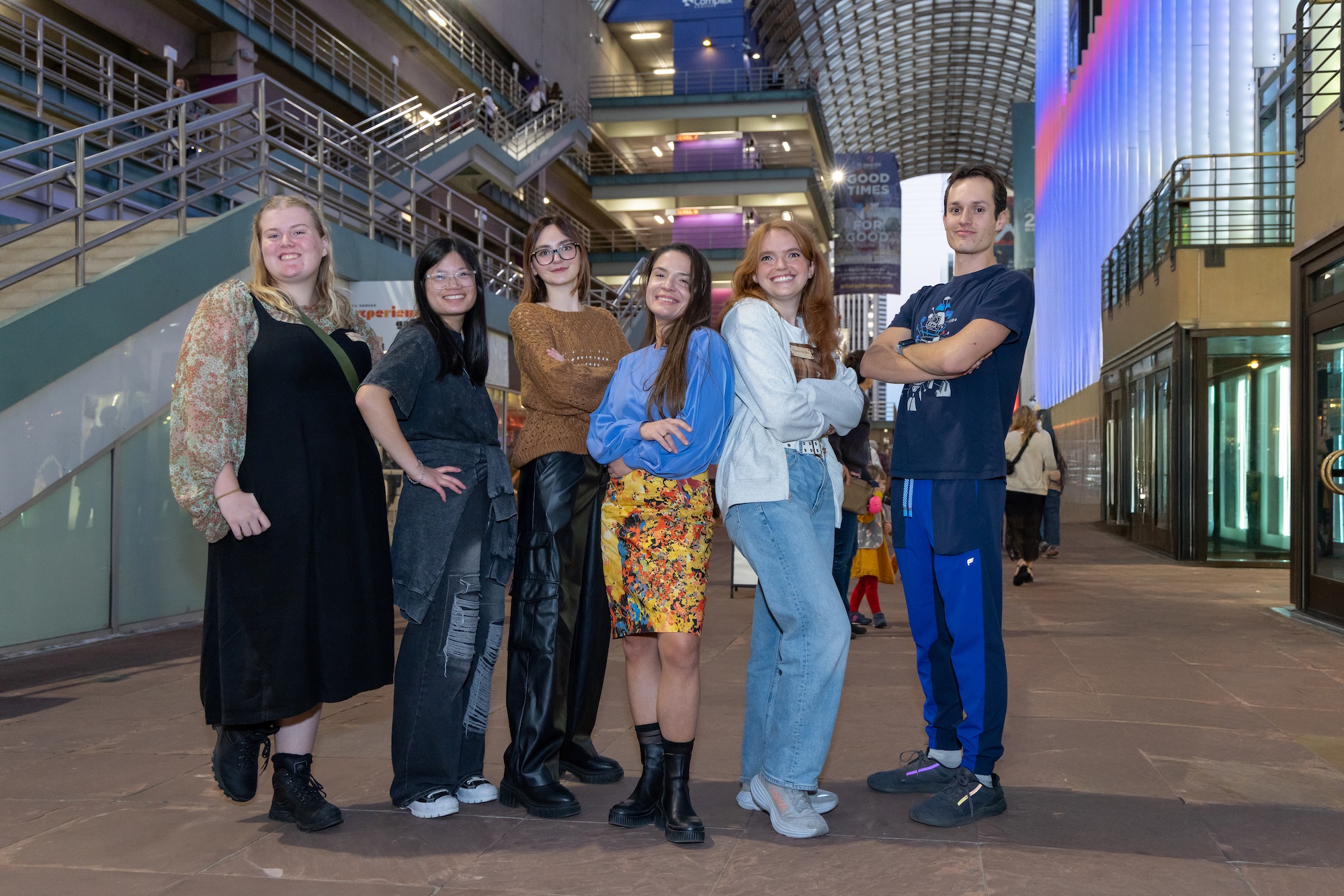 Group of six people standing in an atrium smiling