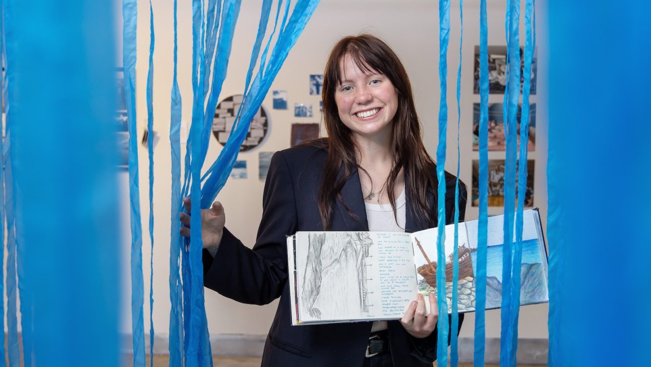 Megan Hatak smiles will holding a sketchbook.