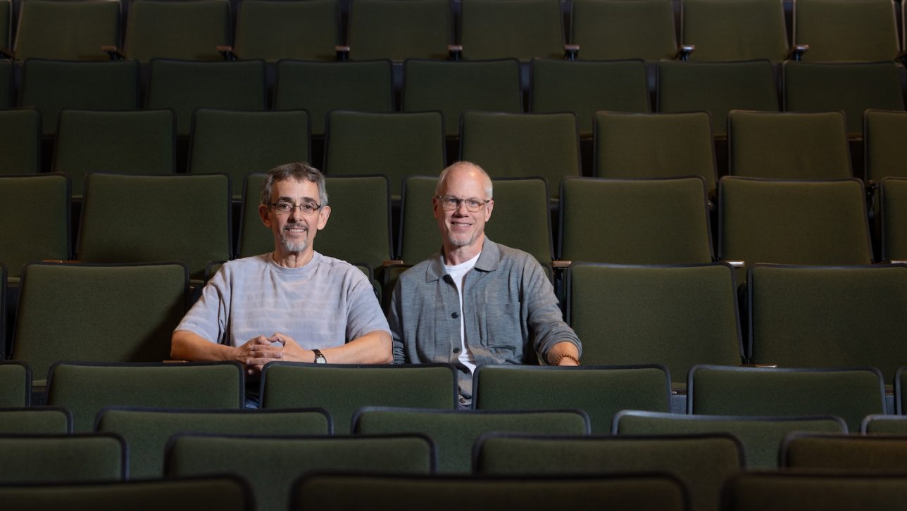 David Liban (left) and Chris Beeson (right) sit in an auditorium next to each other