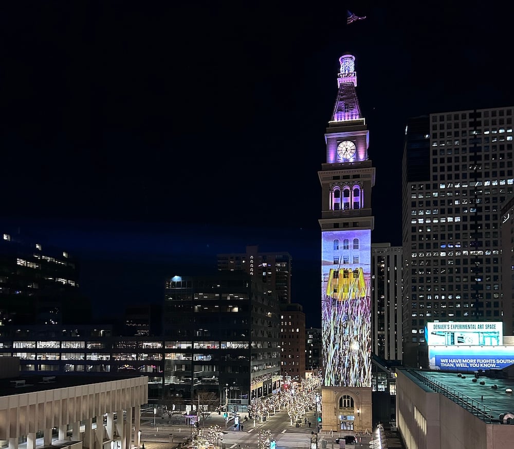 An artwork featuring grass and the beach is projected onto a clocktower