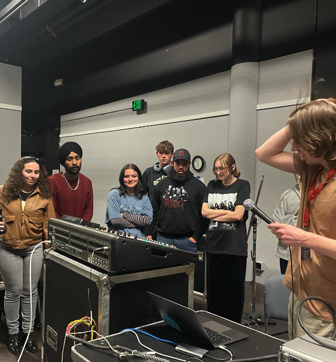 group of students huddled around a sound board